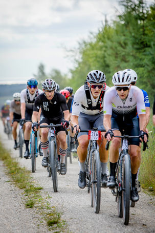 Group of gravel cyclists going uphill on a forest track
