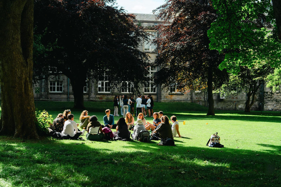 Students sitting together in a circle on the grass at St Andrews.