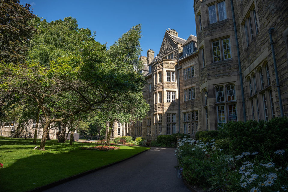 Historic university buildings in St Andrews with gardens and trees.