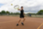 An ISSOS student playing tennis, captured mid-swing on the court during the Tennis elective.