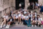 ISSOS students sitting together on steps during a trip.