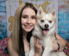 Dog mom poses with small dog for his birthday photo shoot.