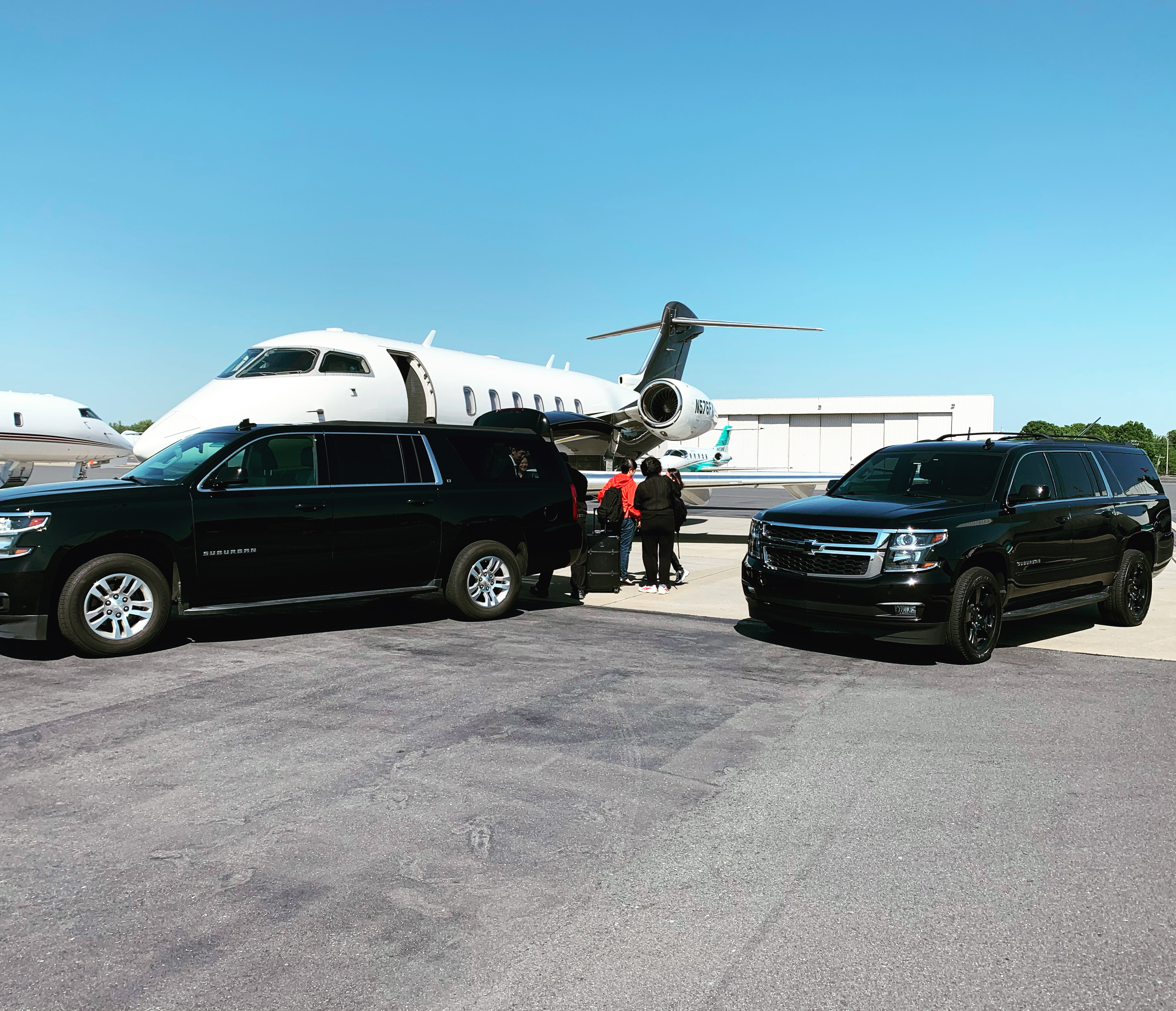 Two CharlotteLUX Luxury SUVs in Front of an Airplane