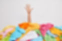 Unrecognizable human raises arm reaches out heap of colorful unfolded clothes busy doing w