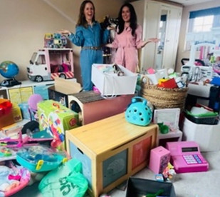 Alix and Georgina stand in a playroom covered in toys