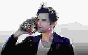 Brandon Flowers holding a seashell to his ear