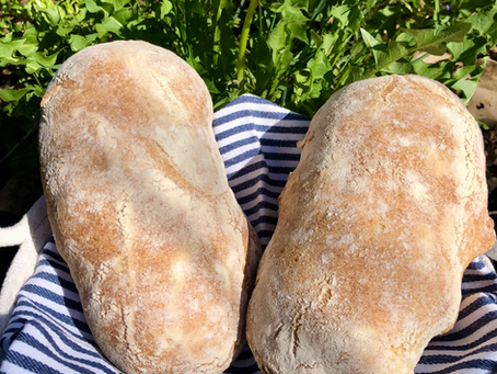 Zwei Ciabatta in einem Brotkorb auf einer blau weiss gestreiften Serviette.