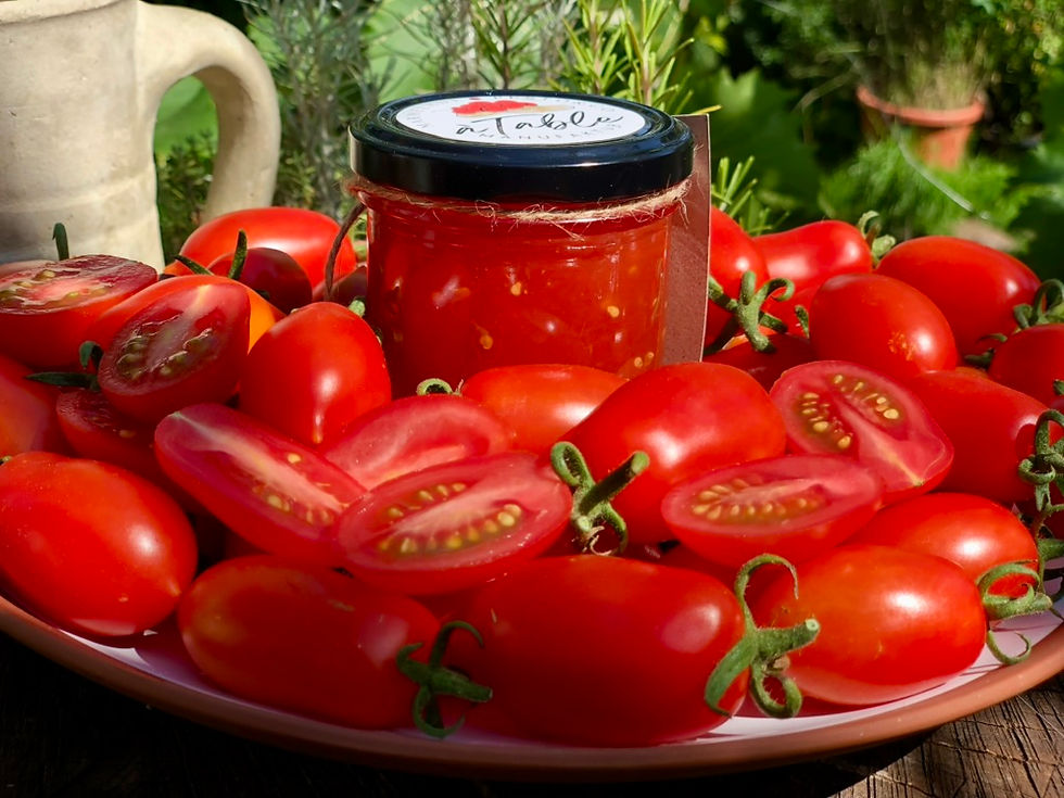 Ein Glas Tomaten-Fruchtaufstrich Badische Pomodori in mitten kleiner, roter Tomaten teils aufgeschnitten 