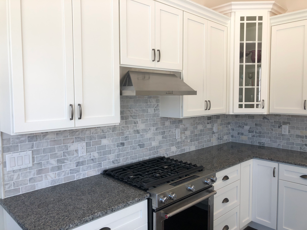 White kitchen cabinets with stainless steel range hood, featuring kitchen remodeling by Ryan Davis Contracting