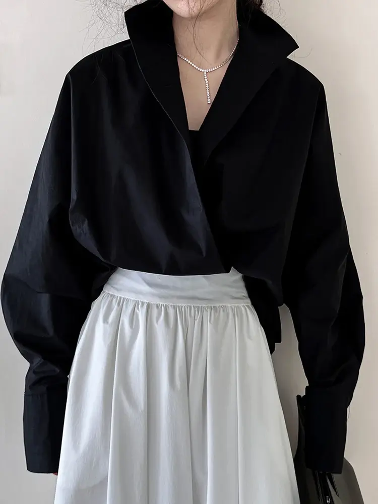 A black and white jersey V-neck tunic with a loose fit, V-neckline, and long sleeves. Made from a cotton-polyester blend