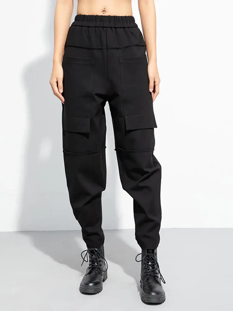 Black relaxed-fit harem pants with high waist, cutout details, and elastic waistband. Cotton-poly blend.