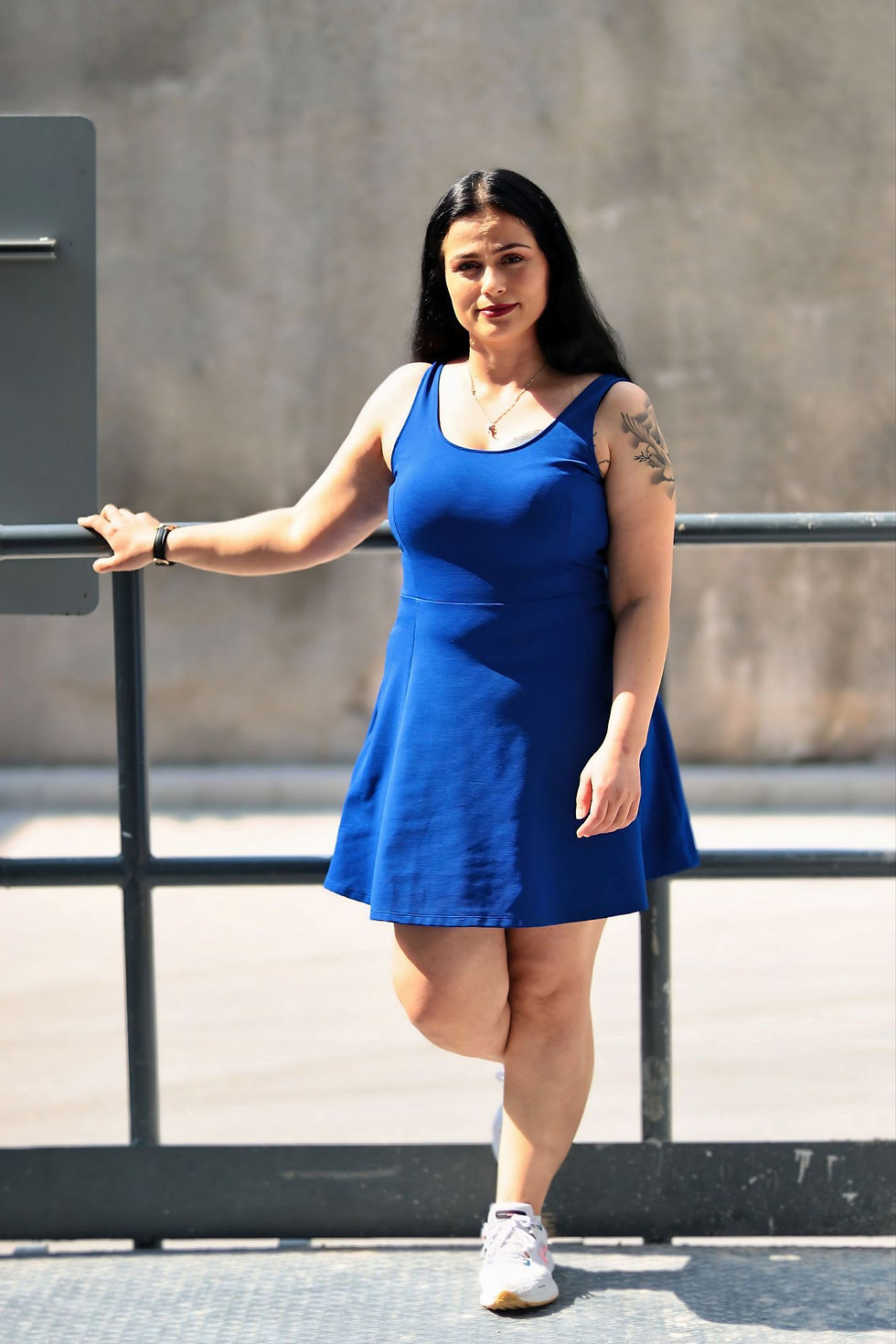 Woman in a vivid blue dress posing by a railing