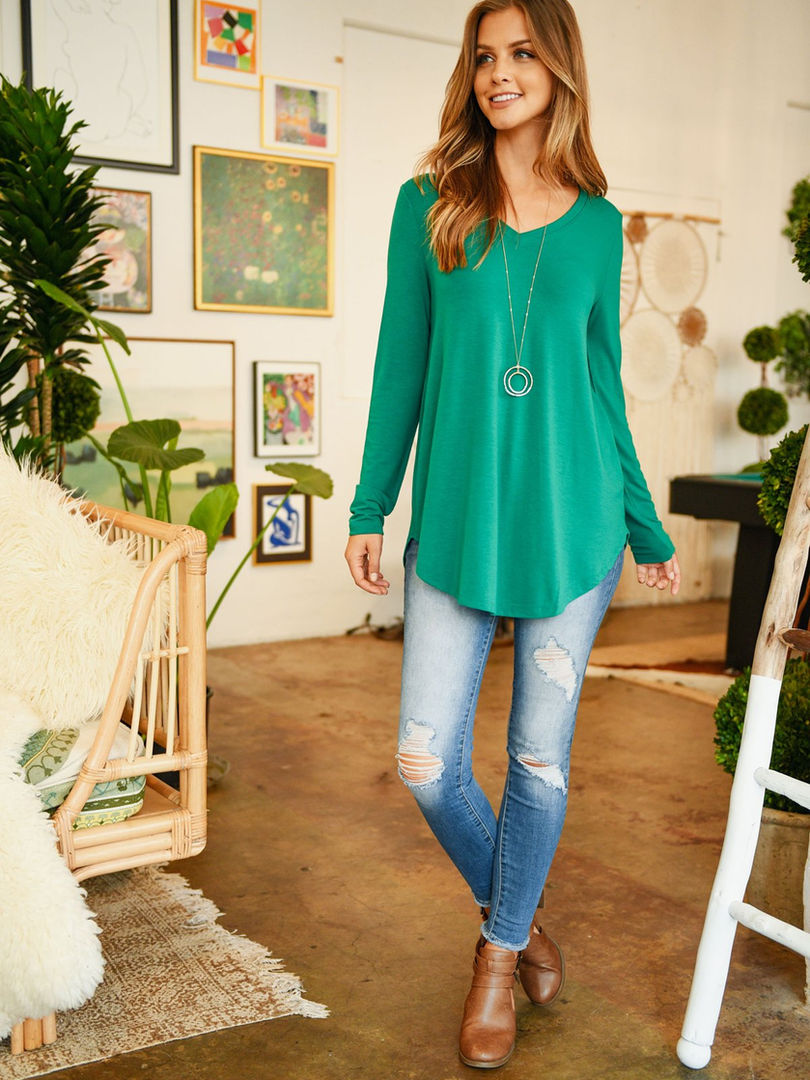 A photo of a model wearing a long-sleeve V-neck top in a soft, fall-colored fabric.