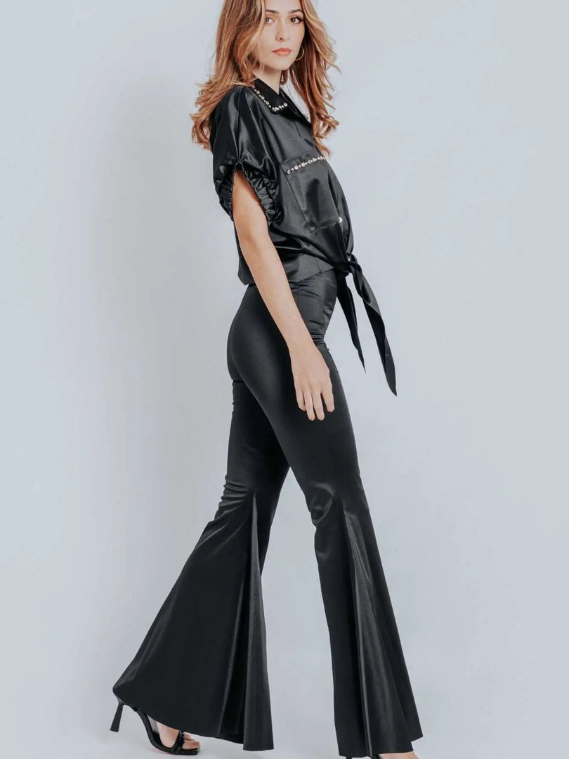 A woman wearing high-waisted black Cusuti flare pants with a form-fitting silhouette that flows into a flared leg.