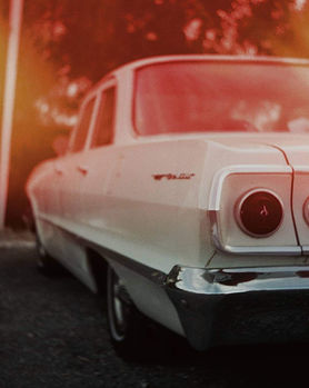back of white vintage car with orange light leak coming through the top