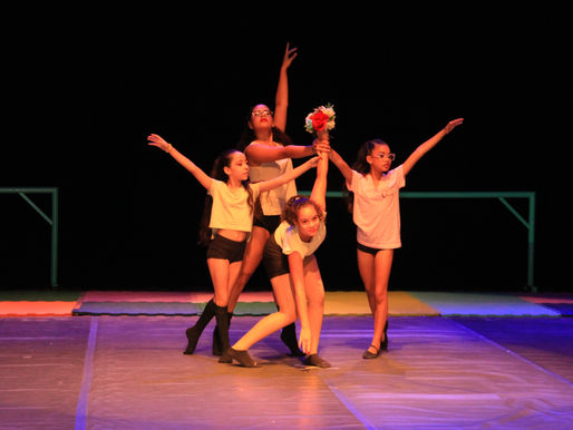 Grupo de alunas juntas no meio do palco em apresentação.