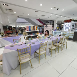 Mesa rectangular con mantel blanco y sillas Tiffany doradas en centro comercial - Fiestalandia Panamá