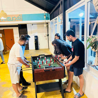 Lively game of foosball between hostel guests, creating instant friendships through shared fun.