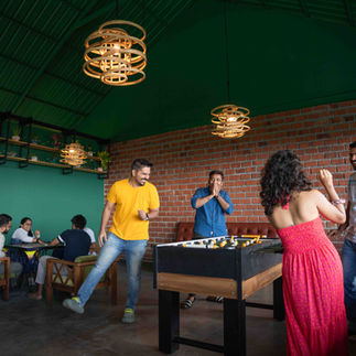 Backpackers cheering during a foosball match in the common area, full of energy and connection.