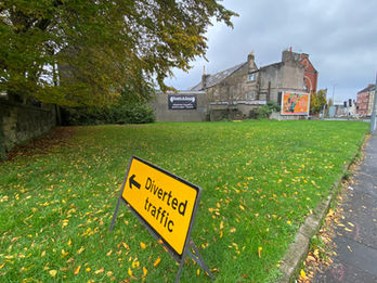 Open space with grass with a 'diverted traffic sign'.