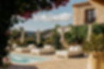 A serene view of a hammock near a crystal-clear pool, surrounded by olive groves, bougainvilla flowers, and a tranquil village nestled in the Costa Blanca mountains.