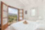 A beautifully decorated, luxurious bedroom with a large window showcasing stunning mountain views in the Costa Blanca region.