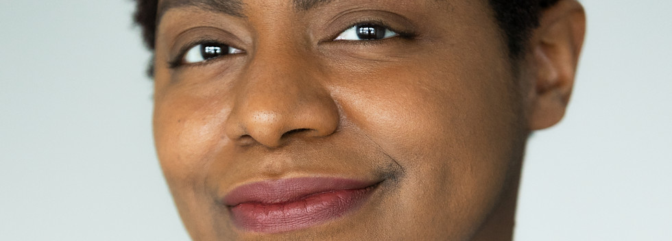 Laura Smith - a brown-skinned Black professional - with a closed mouth smile and a dimple evident on one cheek