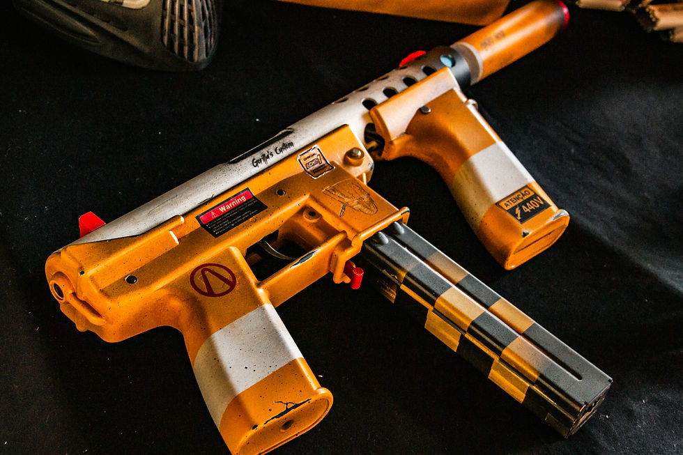 Close-up de equipamento de airsoft tático com rifle e máscara em cenário desértico