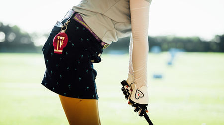 Photo from the side of a woman getting ready for her golf shot at a driving range at a golf tournament of Porsche