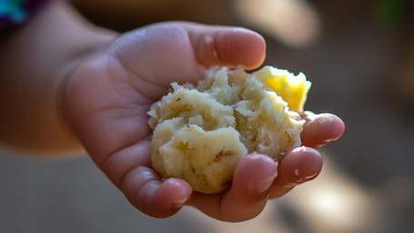 Kind, dass eine Kartoffel zerdrückt