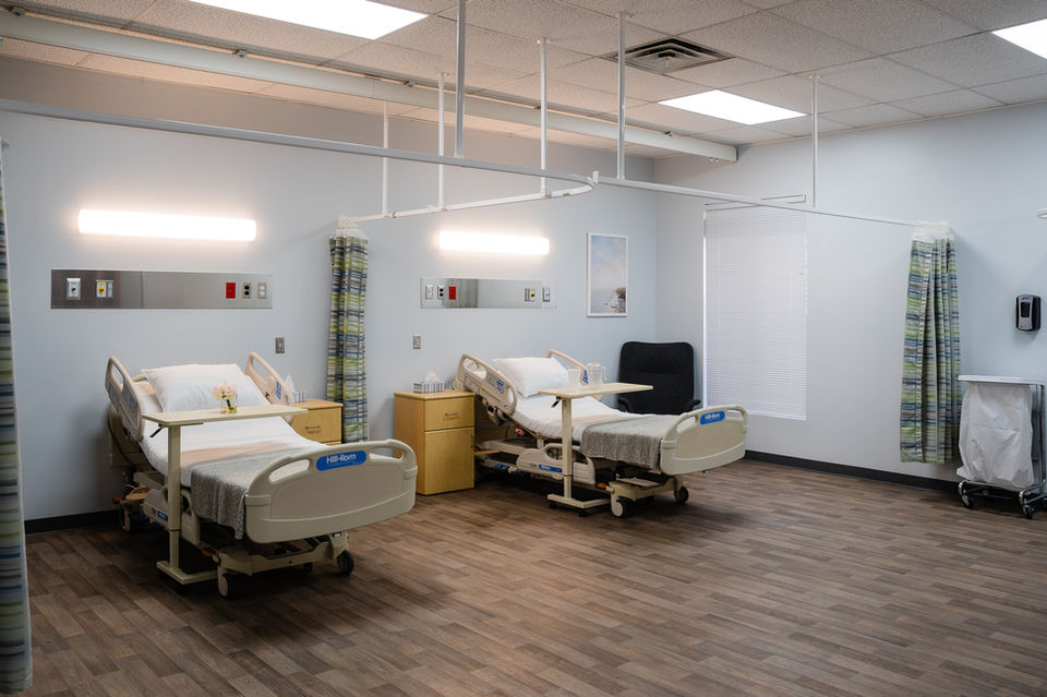 Hospital room with two beds and ceiling-mounted curtain track system without curtains