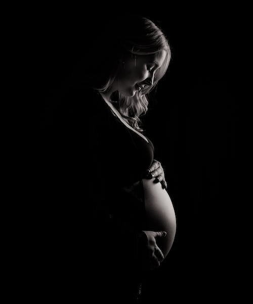 A 40 year old pregnant woman touching her belly