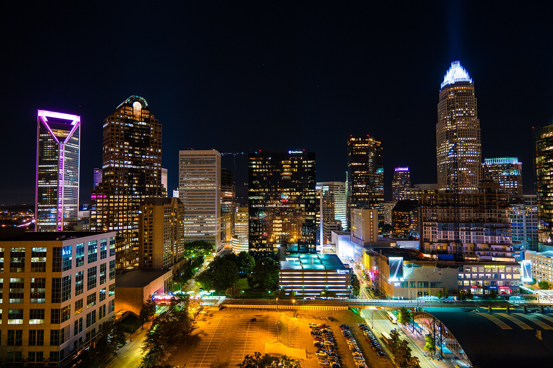 An elevated evening view of Uptown Charlotte, with illuminated buildings and streets below