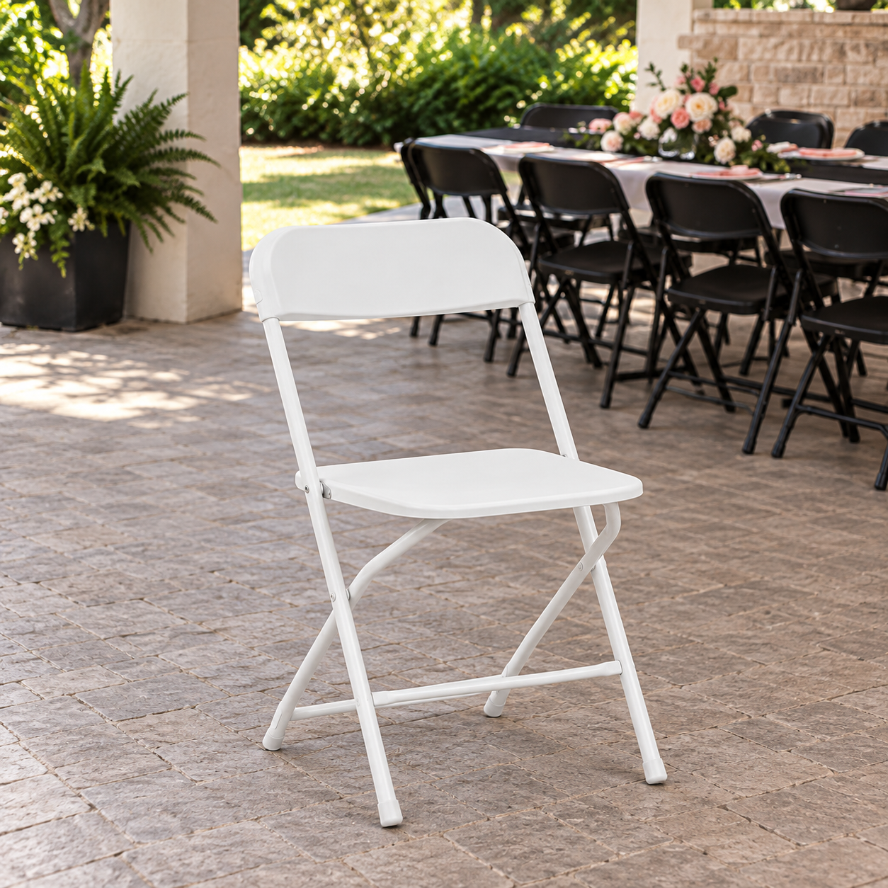 White folding chair on a stone patio with an event table in the background