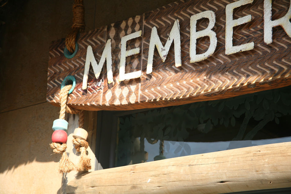 Close-up of a handcrafted “MEMBERS” sign with wood pattern and rope detailing.