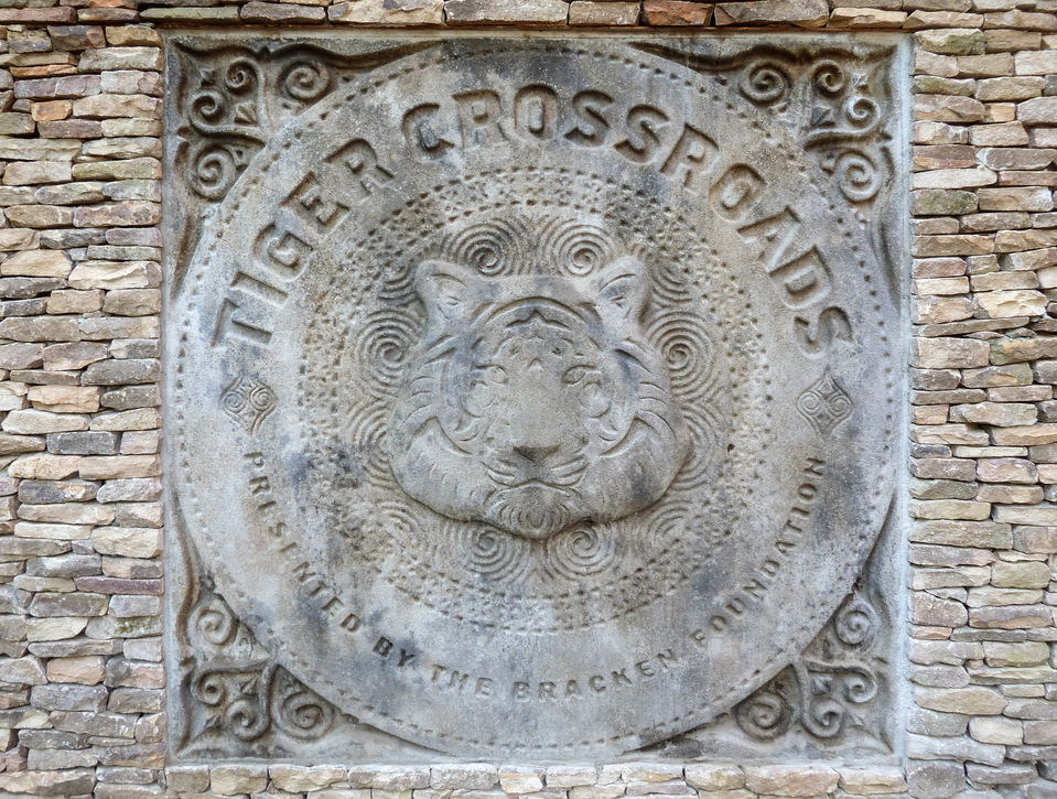 Stone relief sculpture labeled “Tiger Crossroads” with an engraved tiger face and decorative border.