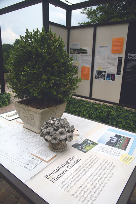 Tabletop display labeled “Revitalizing a Historic Garden” with printed maps, handouts, and decorative potted plant.