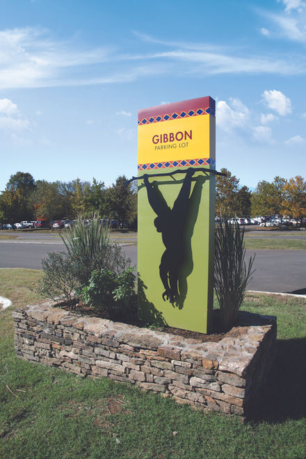 Freestanding sign featuring a silhouetted gibbon hanging from a branch, marking the gibbon habitat at the zoo.