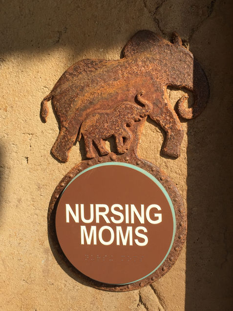 “NURSING MOMS” room sign featuring a carved relief of a mother elephant and calf.