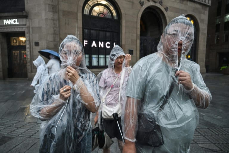 Pessoas se protegem com capas de chuva descartáveis enquanto o Tufão Co-May atinge Xangai (Hector RETAMAL) (Hector RETAMAL/AFP/AFP)