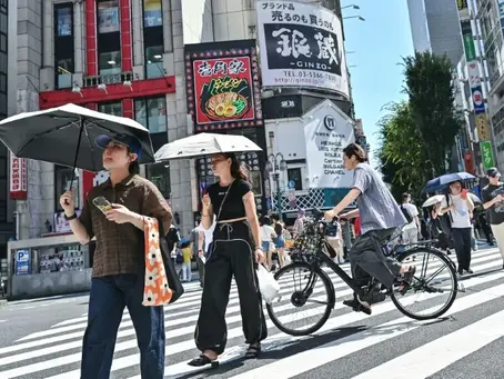 Fußgänger schützen sich mit Regenschirmen vor der Sonne, während sie eine Straße im Vergnügungsviertel Kabukicho in Shinjuku im Zentrum Tokios überqueren (Richard A. Brooks). Richard A. Brooks/AFP/AFPLess