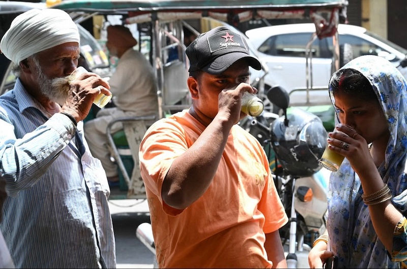 People drink sugarcane juice along a street on a hot summer day in Amritsar on June 18, 2024. Photo: AFP