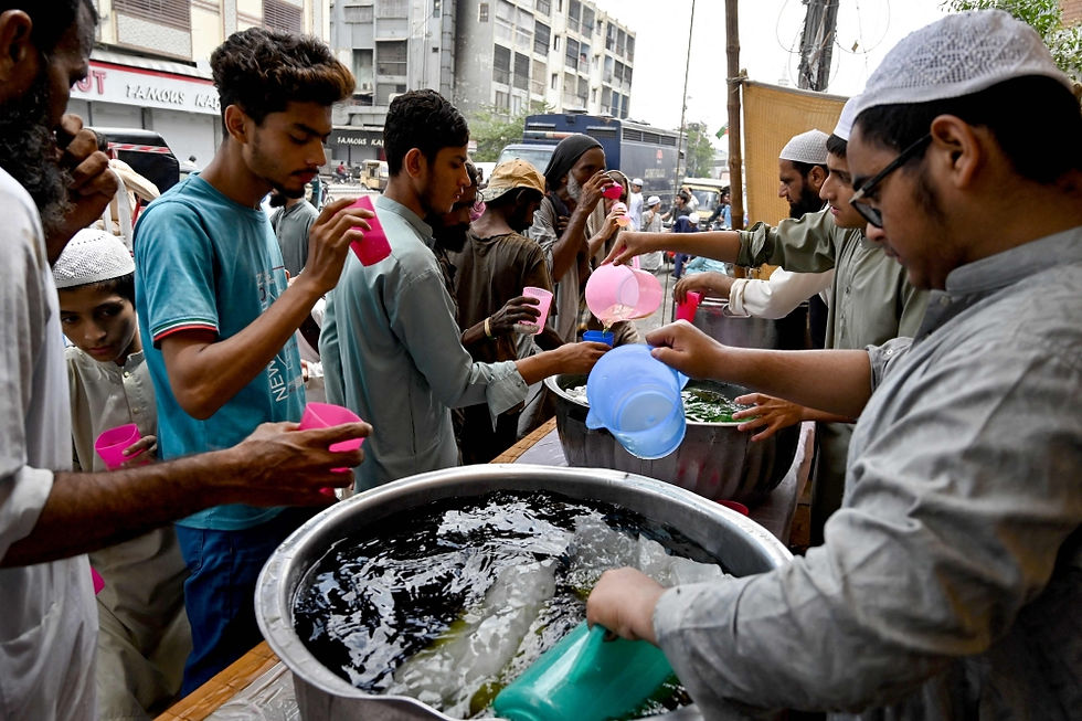 Volunteers hand out cold drinks to people at a heat wave relief camp along a road on a hot summer afternoon in Karachi on June 3, 2024.
