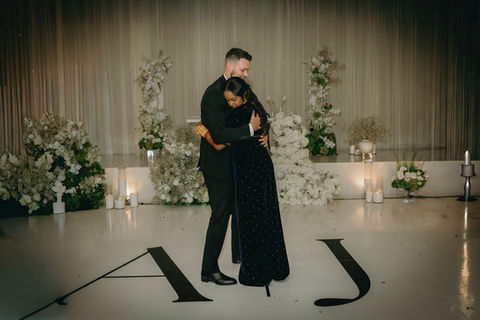 Modern romantic ballroom wedding design featuring a custom white draped backdrop, lush white florals, candlelight, and a statement dance floor at Hilton Seattle Airport & Conference Center designed by Opulent Events Seattle