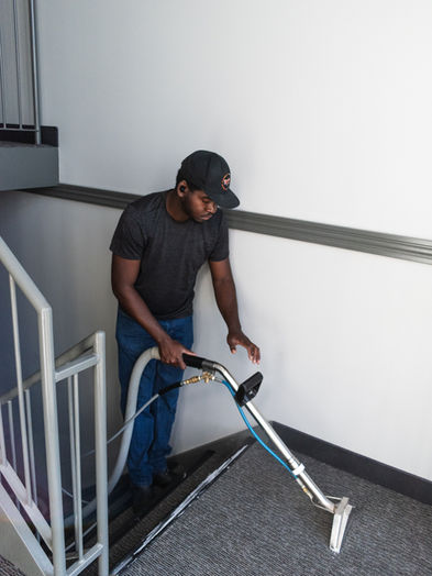 Carpet cleaner cleaning carpets in stairwell.