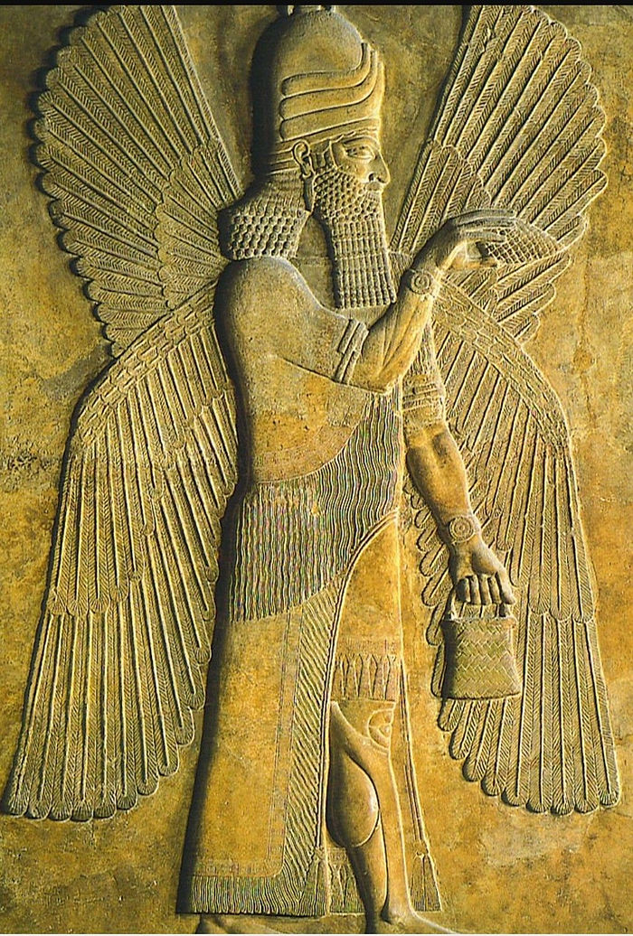 Ancient relief of a bearded figure with wings and helmet, holding a bucket. Detailed carvings on a tan stone background.