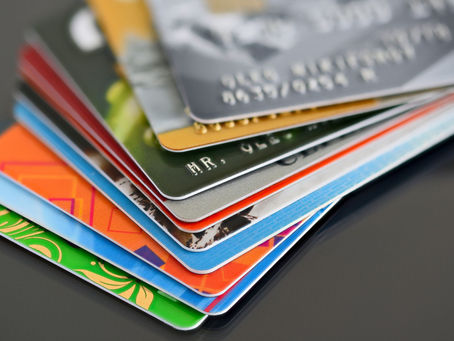UK resident comparing different types of credit cards on a laptop with financial documents on a desk