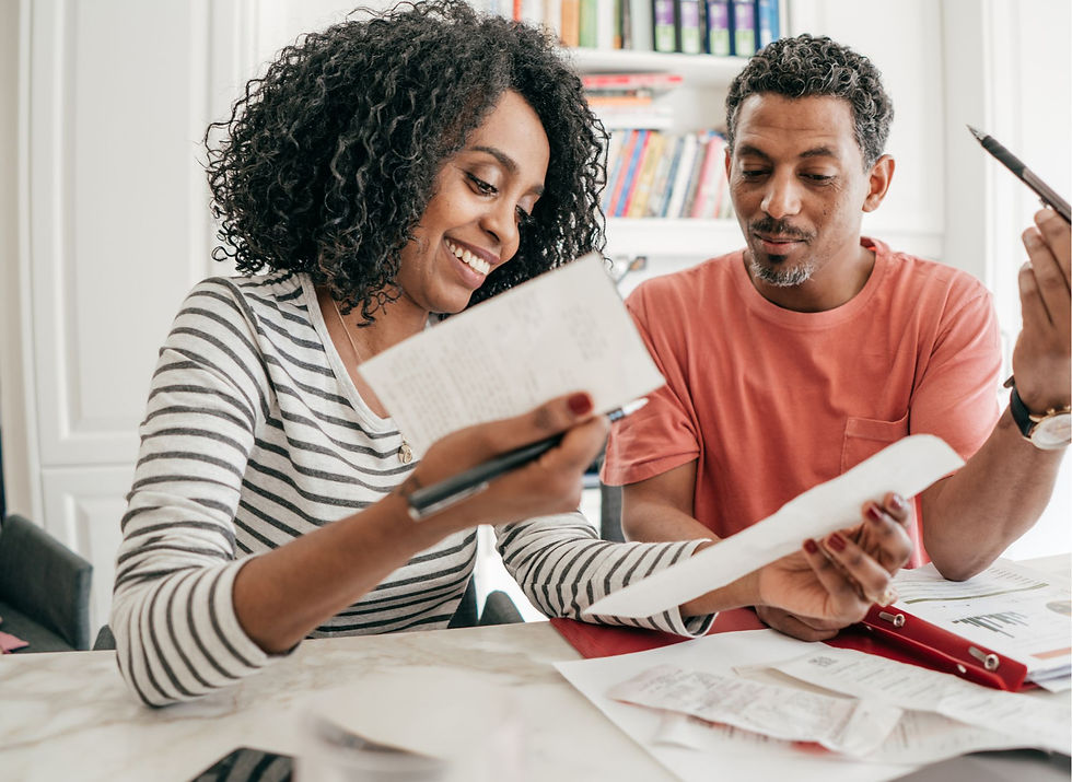 UK resident reviewing a monthly budget on paper with a calculator and bills on a kitchen table