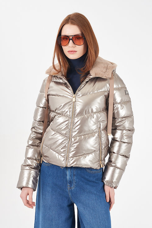 Modelo veste jaqueta puffer dourada, óculos escuros, e calças jeans. Yes Zee Penafiel