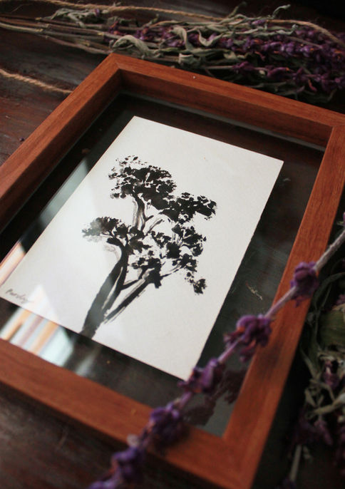 Black print of a plant framed in glass and wood
